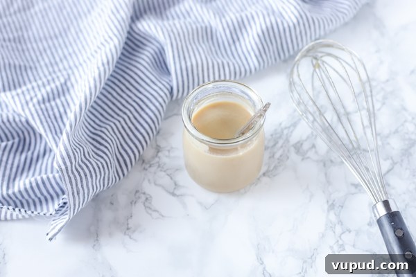 Homemade Sweetened Condensed Milk: Simple Stovetop Recipe 6 homemade sweetened condensed milk in a jar with a whisk to the right