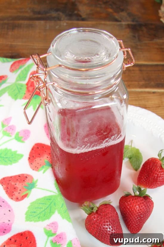 Strawberry Simple Syrup is perfect in cocktails, lemonade, ice teas, and more. A glass jar with a drizzle made with strawberries.
