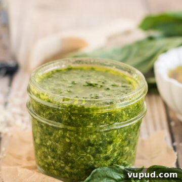 Homemade Nut-Free Pesto Recipe: Flavorful Dairy-Free Sauce 7 nut free basil pesto in a small jar with basil in the background