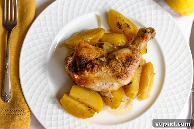 Authentic Greek Lemon Chicken Recipe with Crispy Roast Potatoes 10 Greek lemon chicken served on a white plate alongside a mustard color napkin and serveware.