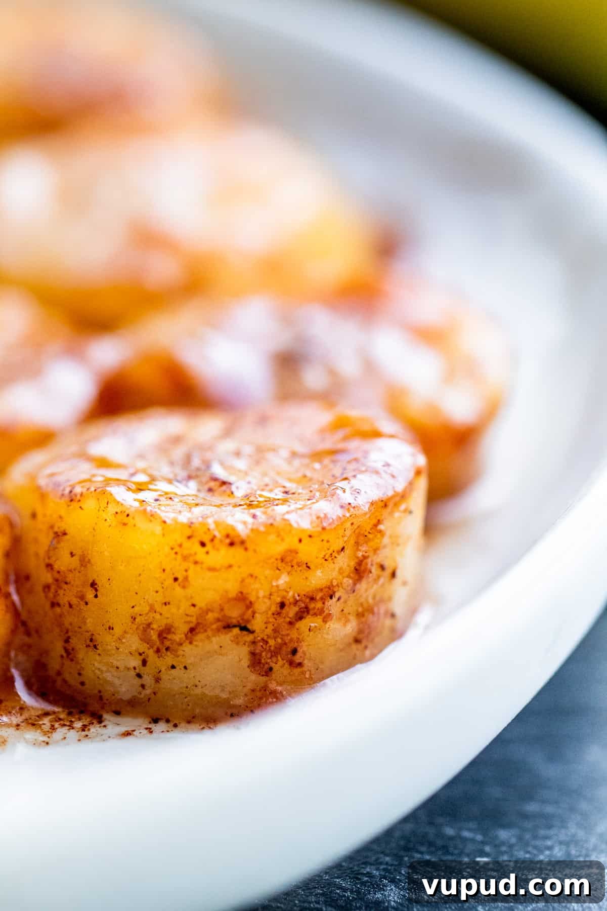 Pan-Fried Cinnamon Bananas with Maple Glaze Recipe 2 Close up shot of fried banana on white plate.