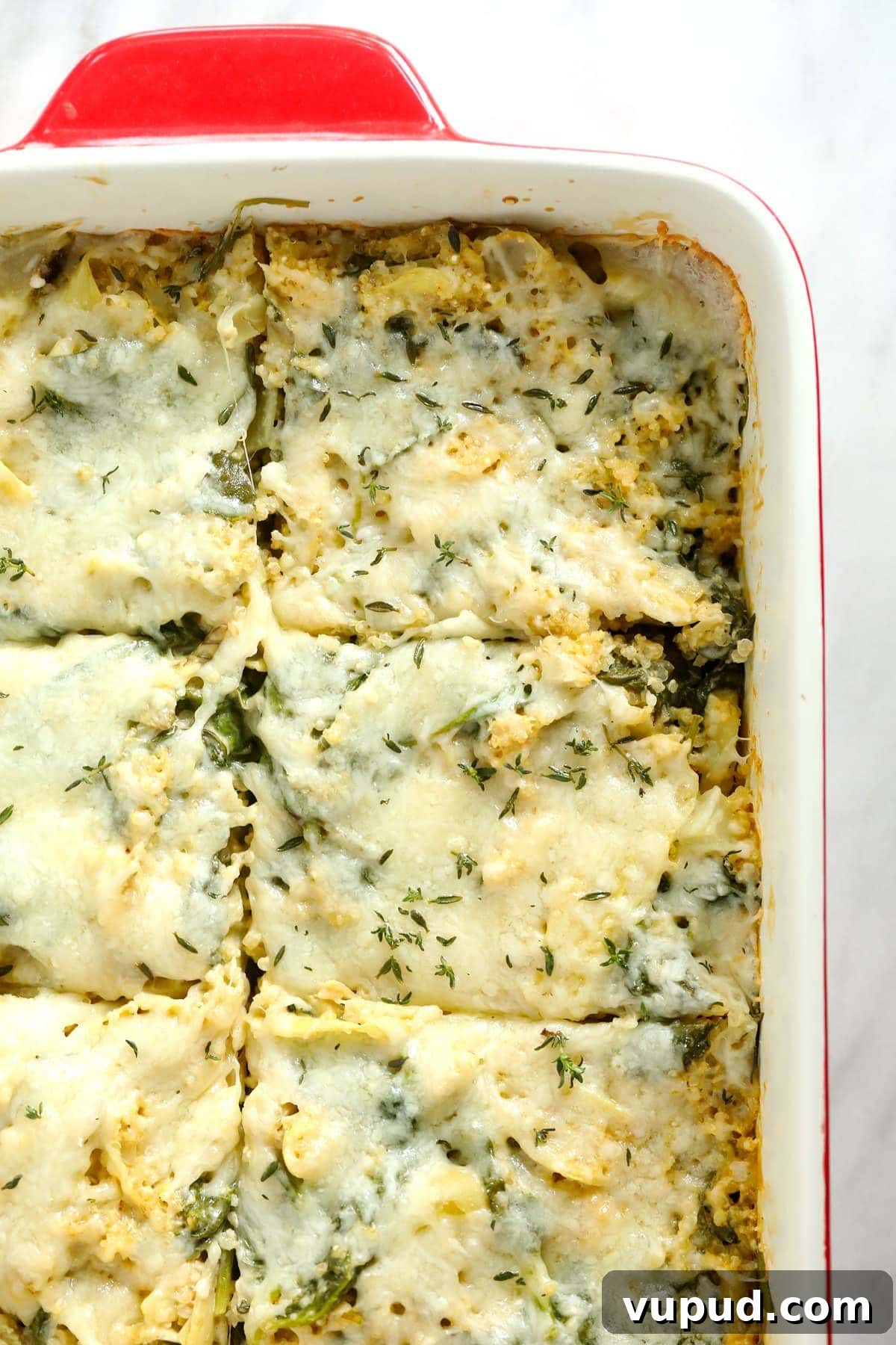 Baked spinach artichoke quinoa casserole with cheese on top. 