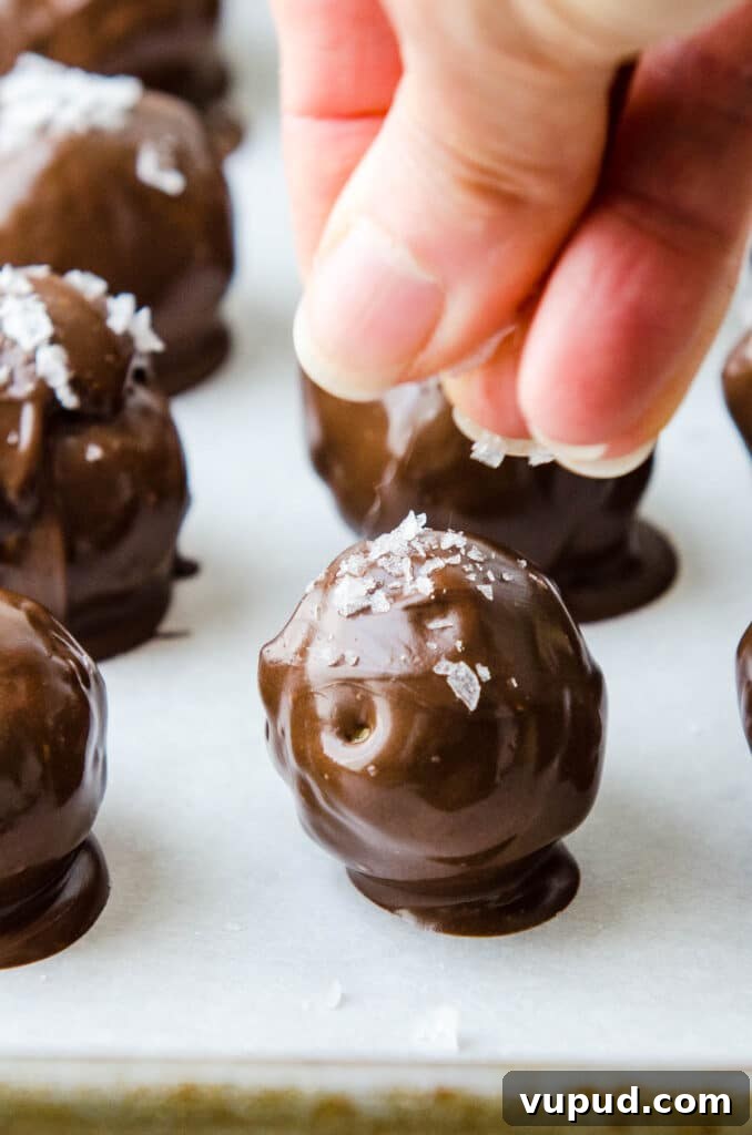 No-Bake Peanut Butter Rice Krispie Balls Dipped in Dark Chocolate 13 sprinkling maldon sea salt on the still wet chocolate coating.