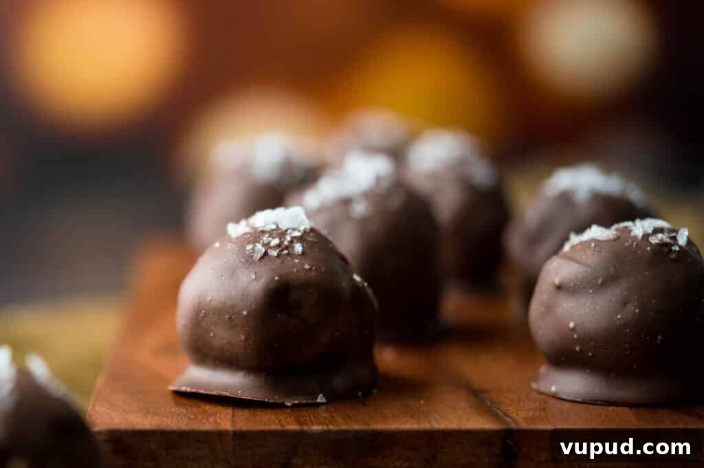 No-Bake Peanut Butter Rice Krispie Balls Dipped in Dark Chocolate 15 A wooden serving board filled with chocolate peanut butter truffles.