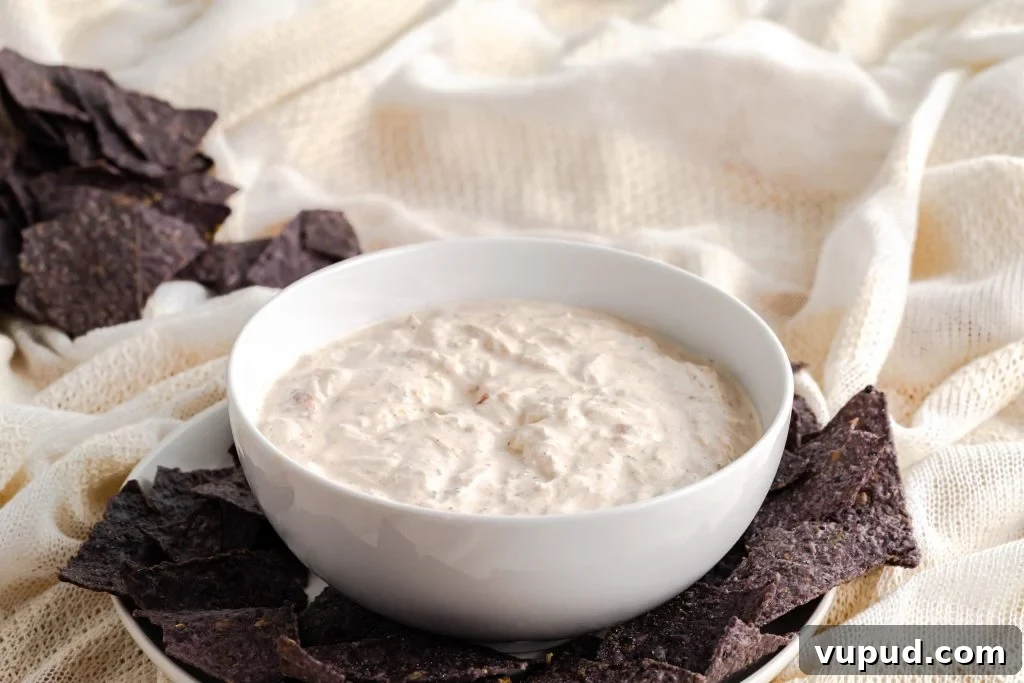 Creamy Mexican Sour Cream Dip Recipe for Parties 5 Blue corn tortilla chips with sour cream dip and stacked chips in the background.