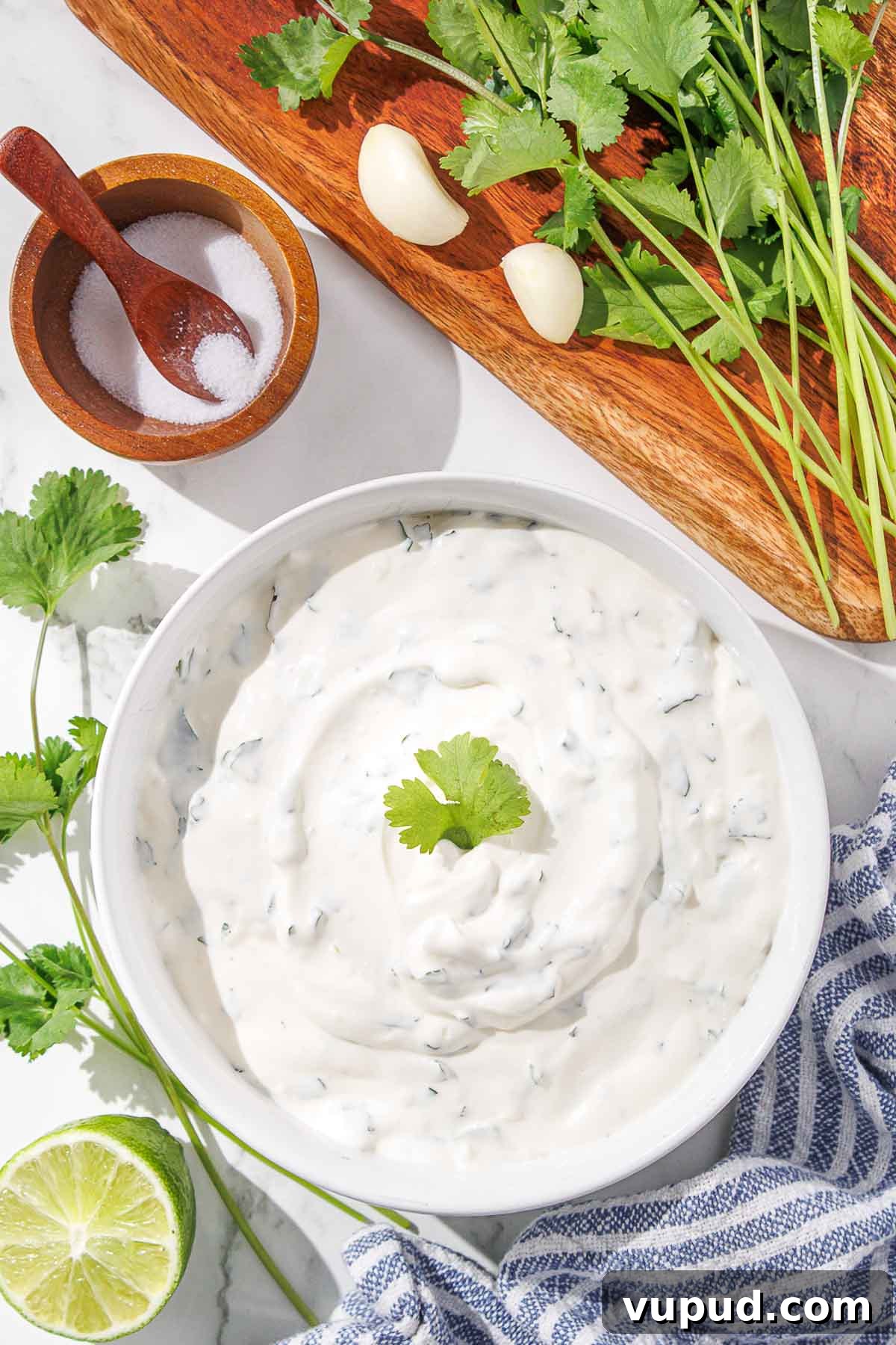 Creamy Cilantro-Lime Crema Recipe for Tacos & Bowls 2 A bowl of creamy cilantro dip with lime, garlic, and salt on a kitchen counter.