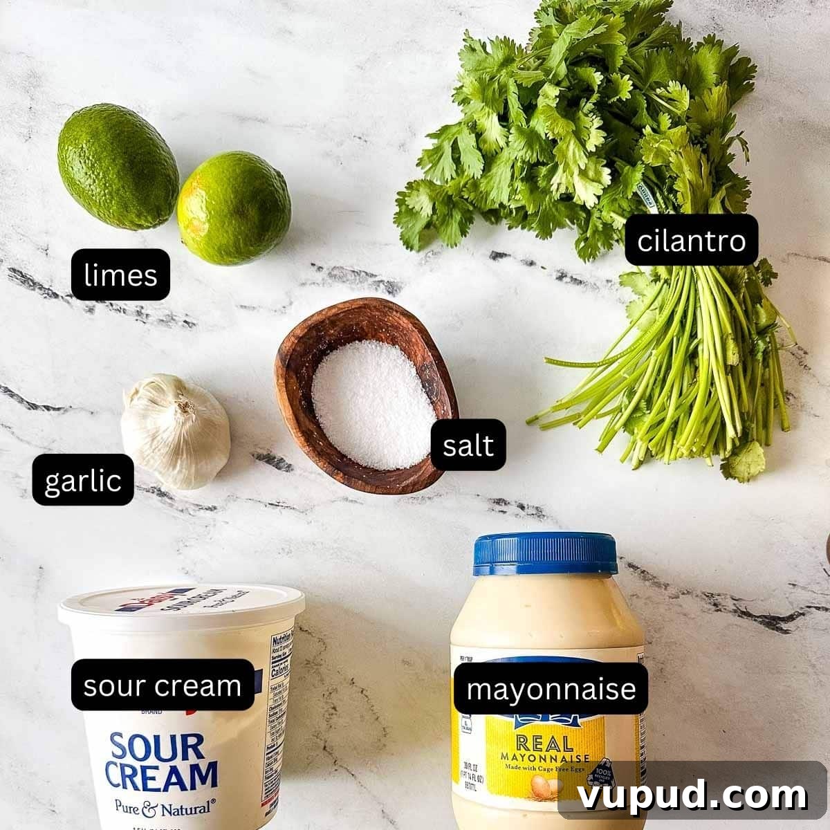 Creamy Cilantro-Lime Crema Recipe for Tacos & Bowls 3 The labeled ingredients for cilantro lime crema sit on a white marble counter.