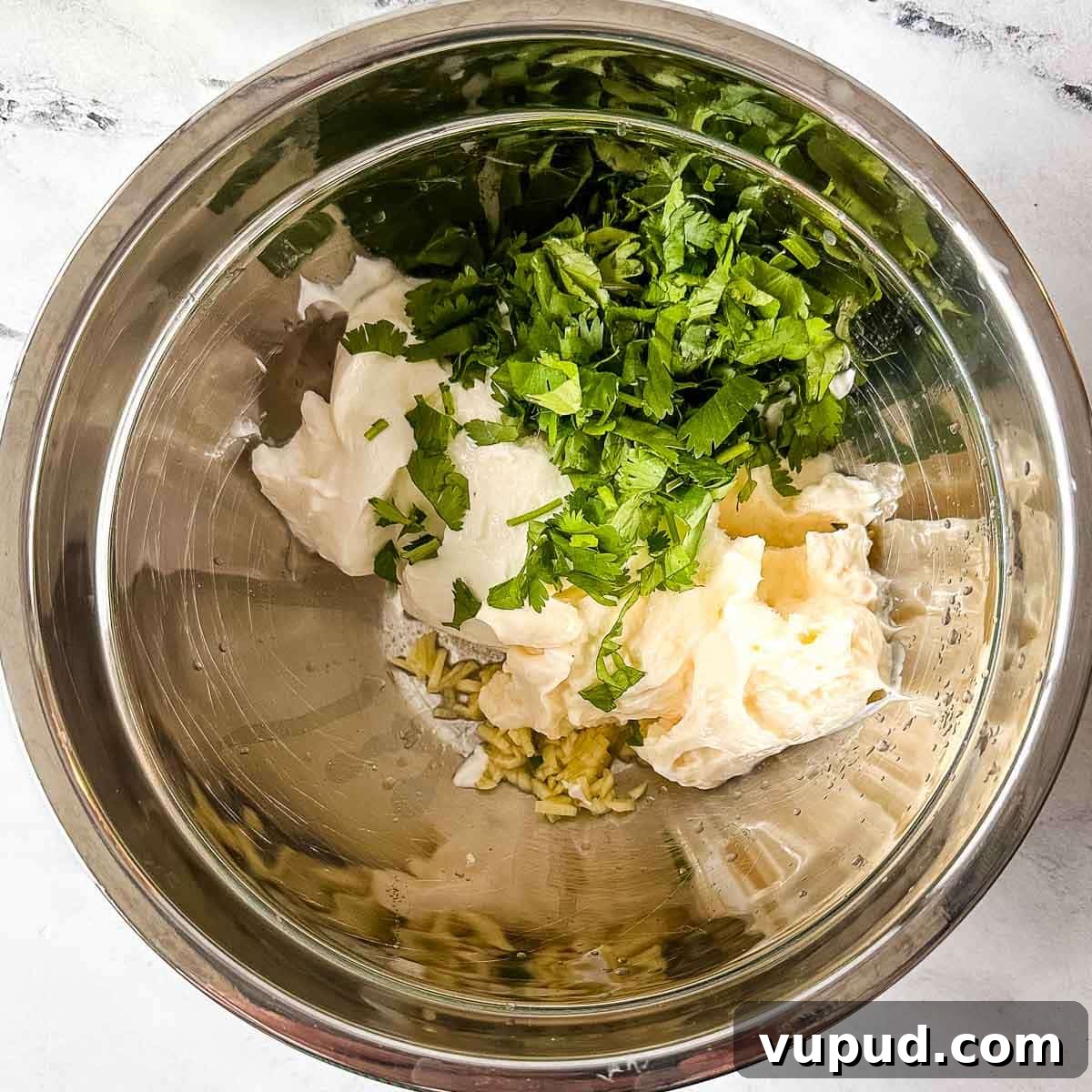 Creamy Cilantro-Lime Crema Recipe for Tacos & Bowls 6 The ingredients for cilantro lime crema in a silver bowl.