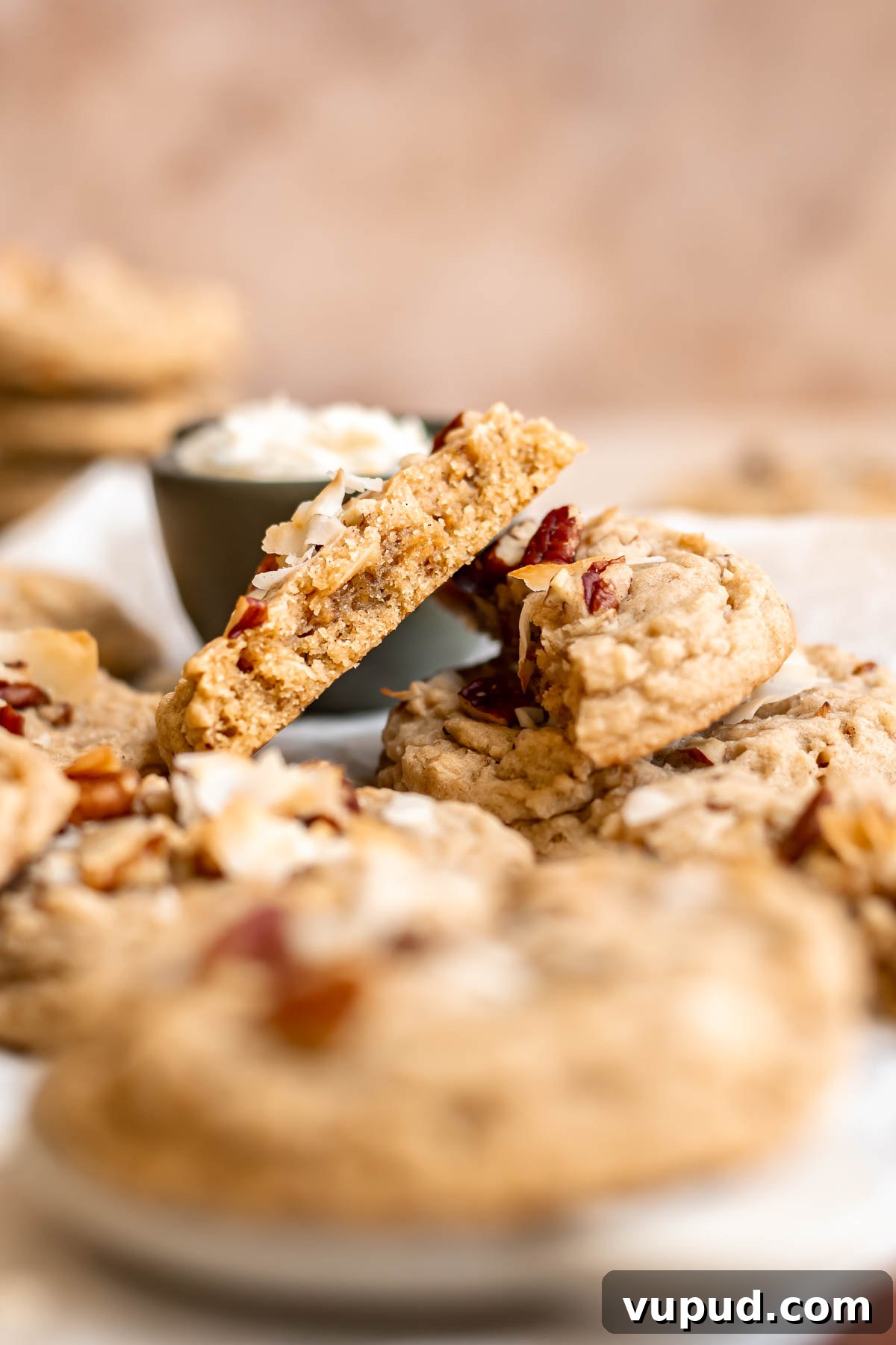 Chewy Coconut Pecan Cookies Recipe for Crispy Edges and Gooey Center 2 A cookie is broken apart and leaning on other cookies.