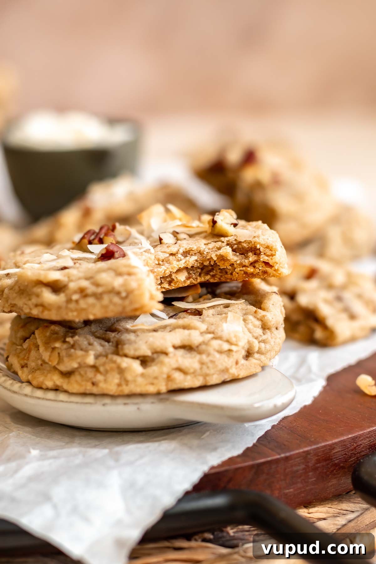 Chewy Coconut Pecan Cookies Recipe for Crispy Edges and Gooey Center 13 Two stacked cookies on a plate. The top cookie has a bite out of it.