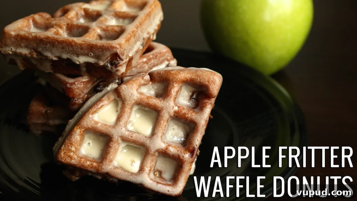 Apple Fritter Waffle Donuts Recipe: Crisp, Cinnamon-Glazed Treats 2 Apple Fritter Waffle Donuts on a black plate with a green apple in the background.