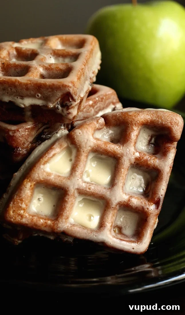 Apple Fritter Waffle Donuts Recipe: Crisp, Cinnamon-Glazed Treats 6 An Apple Fritter Waffle Donut dripping with glaze. More are stacked in the background next to a green apple.