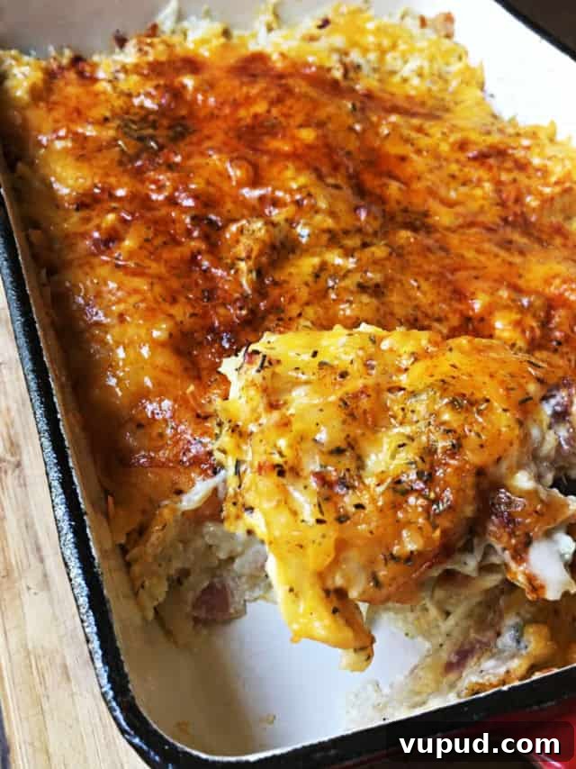 Cheesy Hashbrown Casserole with Crispy Bacon Topping 5 the corner of the casserole scooped out with herbs