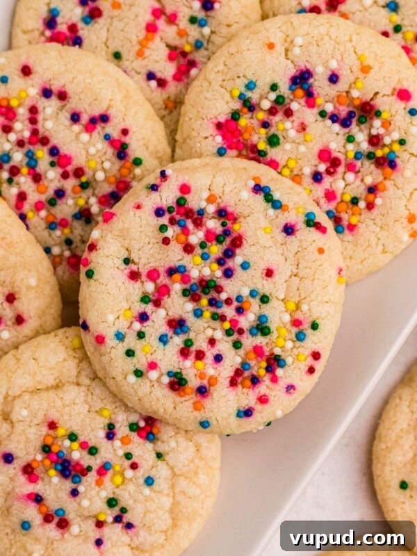Oreo Popcorn Recipe: Creamy Chocolate Cookie Popcorn Treat 11 Sugar cookies topped with sprinkles stacked on a rectangle white plate .