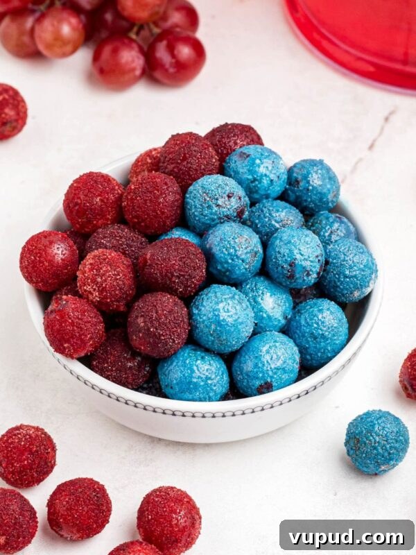 Oreo Popcorn Recipe: Creamy Chocolate Cookie Popcorn Treat 12 Red and blue candy grapes stacked in a white bowl with grapes scattered on a marble table.