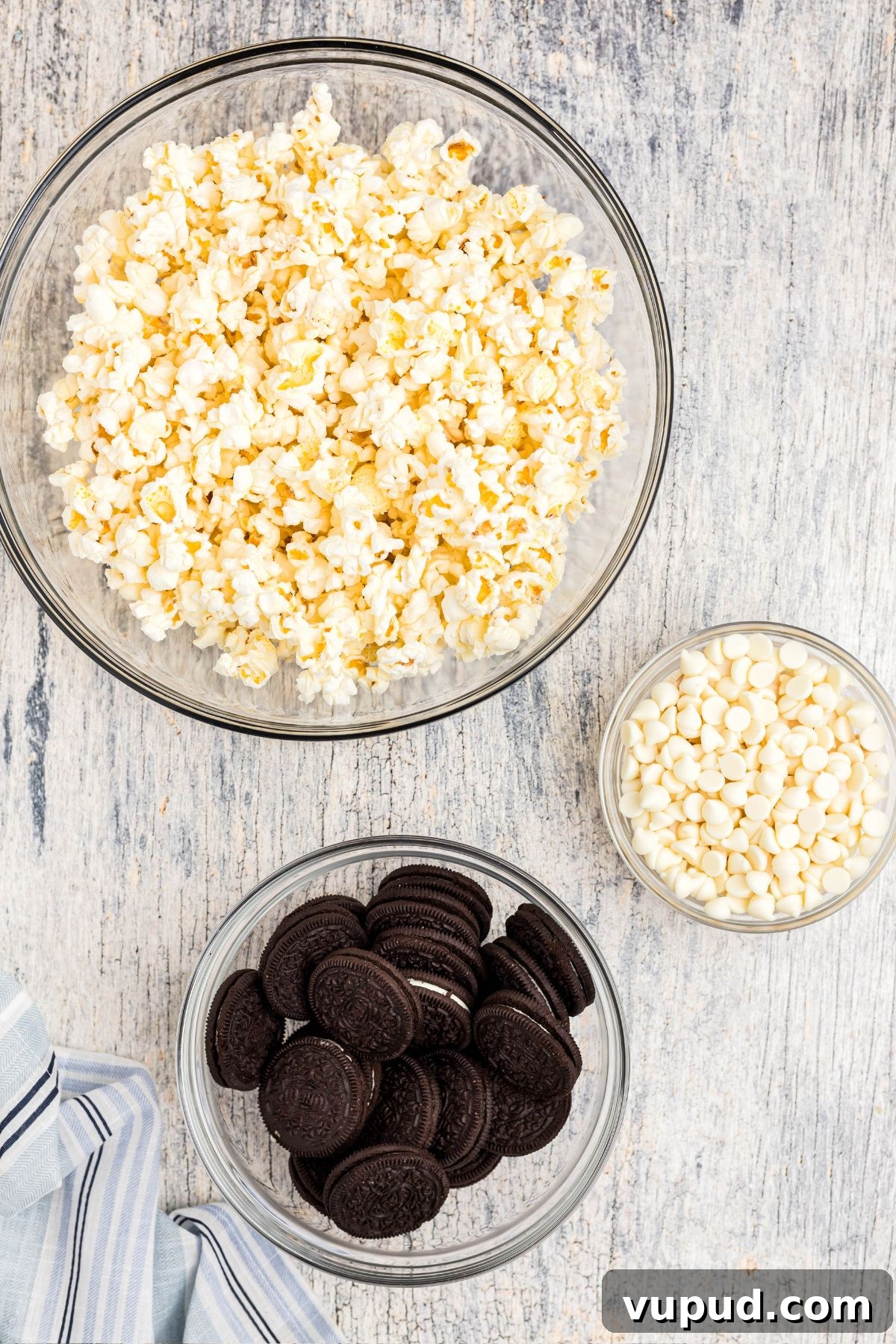Oreo Popcorn Recipe: Creamy Chocolate Cookie Popcorn Treat 3 Ingredients needed to make Oreo popcorn measured into clear glass bowls.