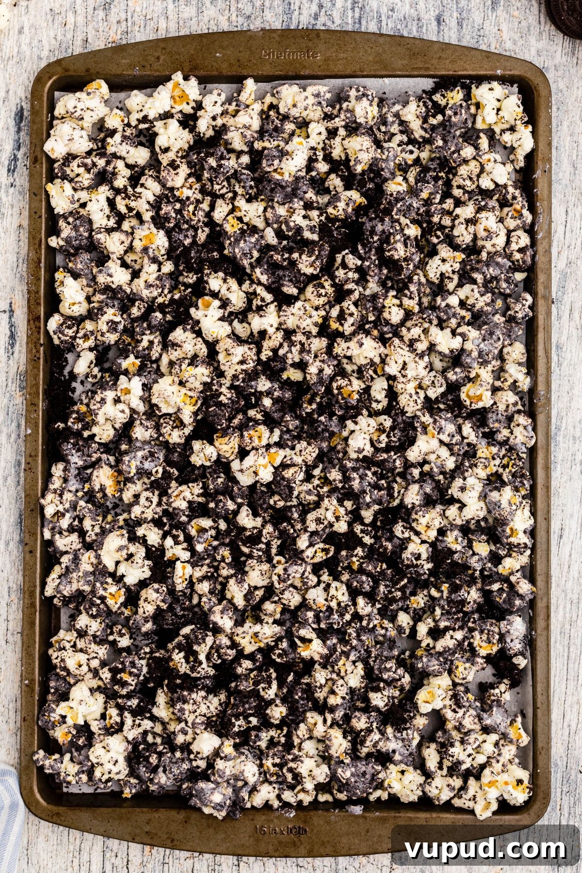 Oreo Popcorn Recipe: Creamy Chocolate Cookie Popcorn Treat 6 White chocolate mixed with crushed Oreos and popcorn, spread out on a baking sheet lined with parchment paper.