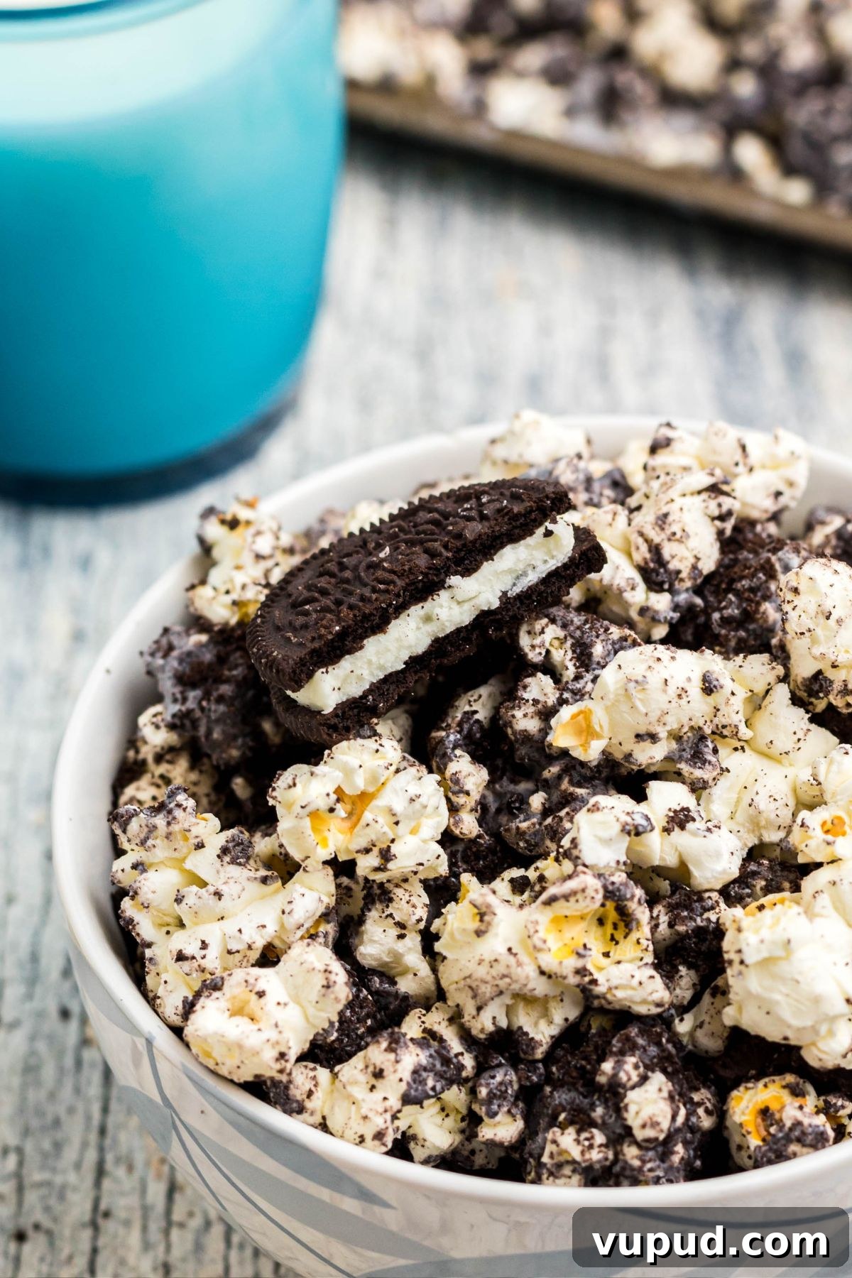 Oreo Popcorn Recipe: Creamy Chocolate Cookie Popcorn Treat 8 Close up photo of an Oreo cookie broken in a bowl of popcorn.