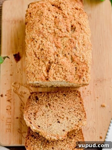 The banana bread with cake flour is on a board with a serrated knife.