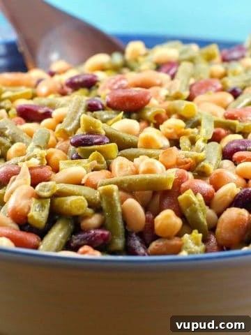Easy (vegan) mixed bean salad in a large bowl with a dark brown wooden spoon