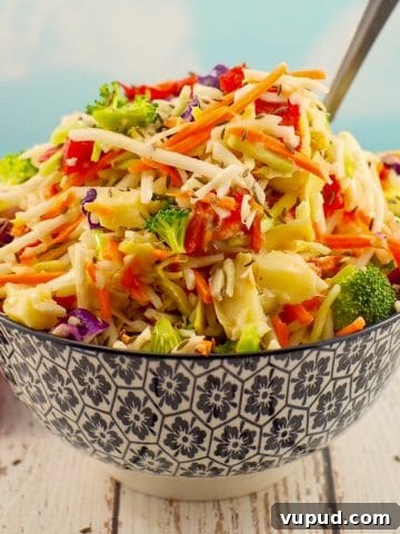 Healthy coleslaw in a black and white patterned bowl with a spoon sticking out of the coleslaw