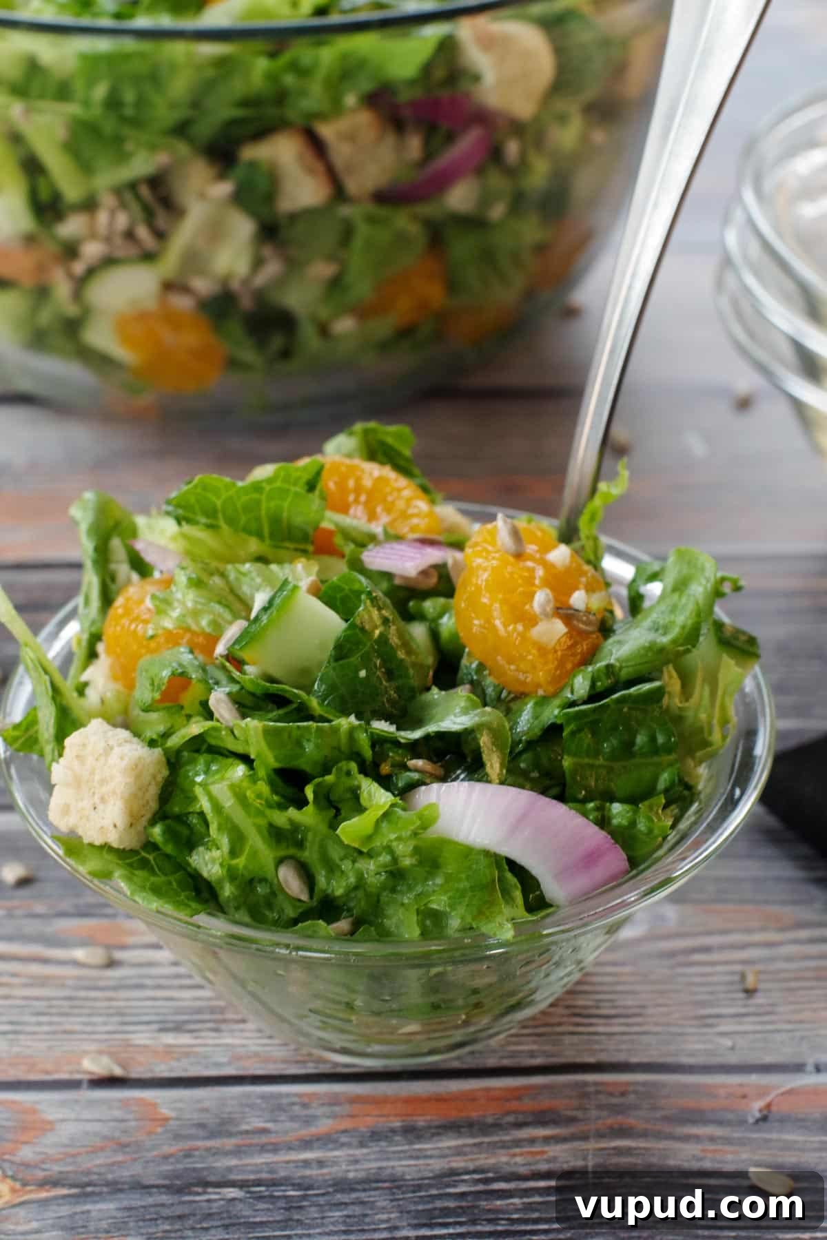 Zesty Mandarin Orange Salad Recipe with Citrus Vinaigrette 9 Mandarin Orange salad in a small glass bowl with a fork with a large glass bowl of salad in background