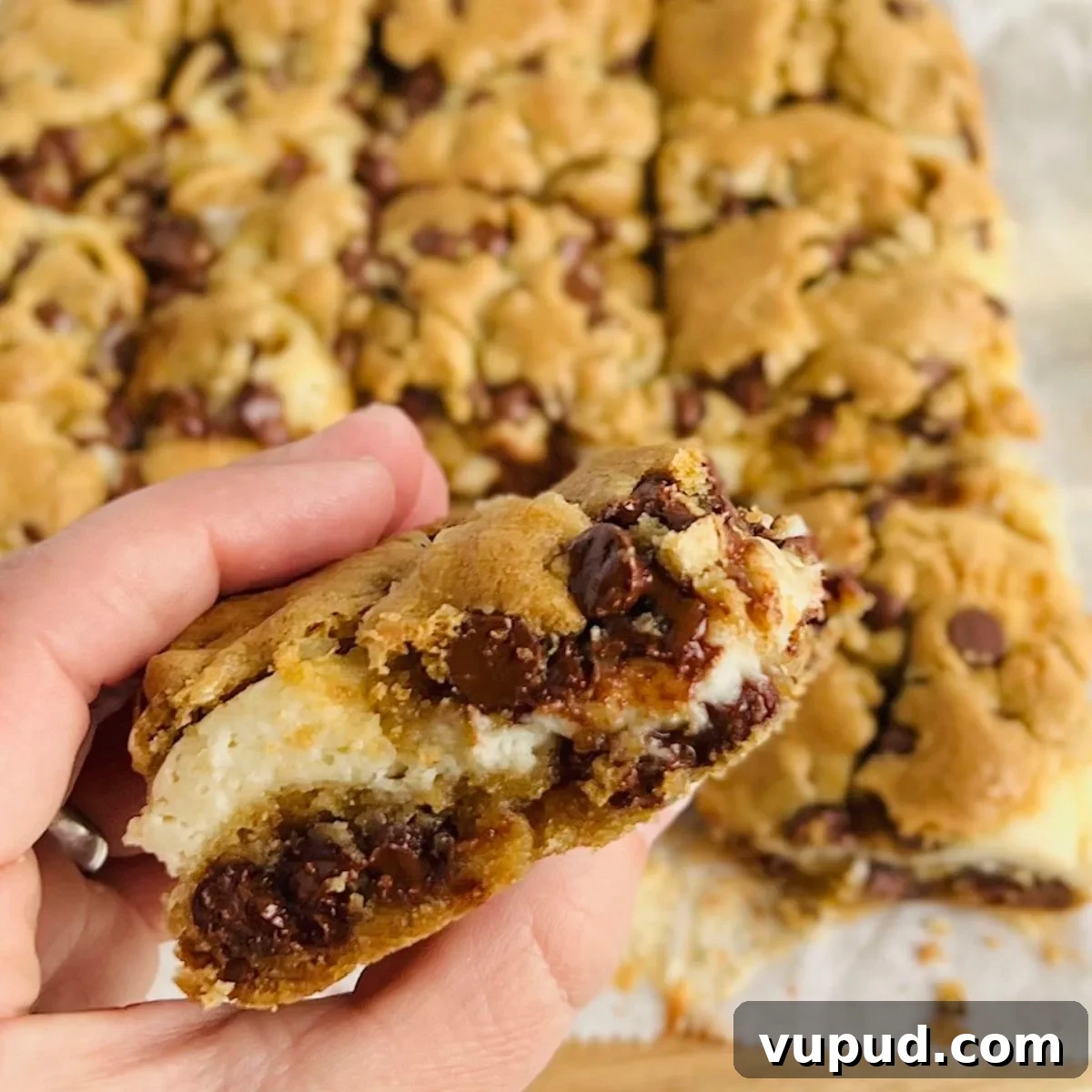 A hand holding a Gluten Free Dairy Free Chocolate Chip Cream Cheese Bar.
