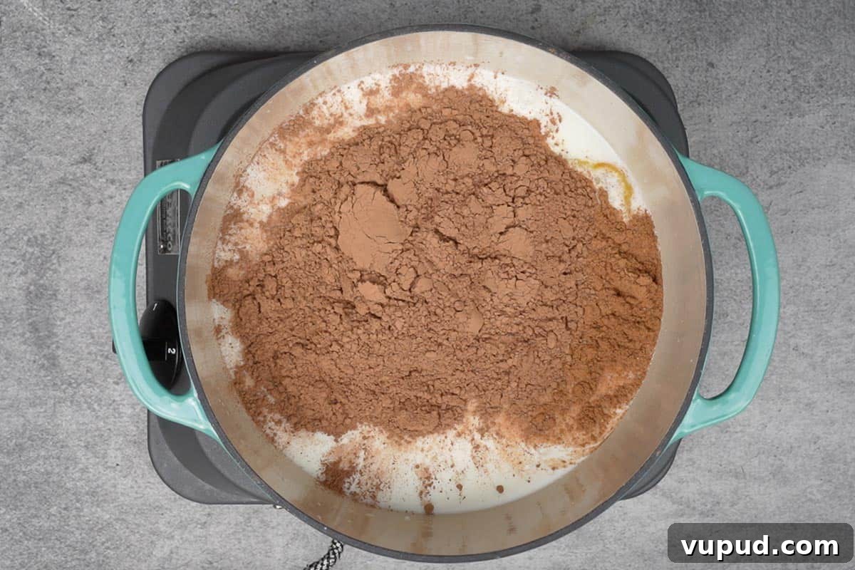 Pumpkin Spice Hot Chocolate: Cozy Autumn Cocoa Recipe 3 Milk, pumpkin puree, pumpkin pie spice, water, sugar and cocoa powder added to a pan.