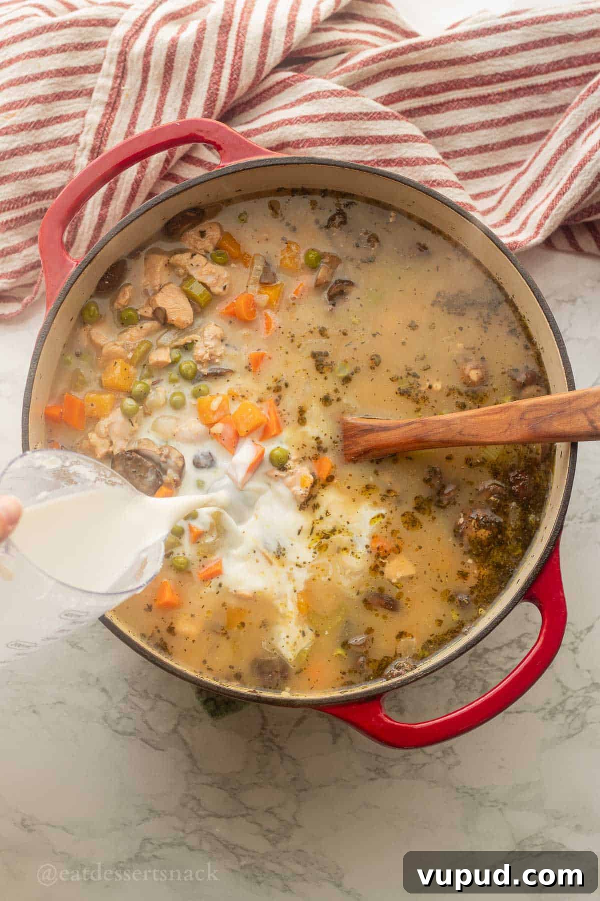 Creamy Chicken and Wild Rice Soup Recipe for Cozy Comfort 7 Pouring milk into soup pot with spoon.