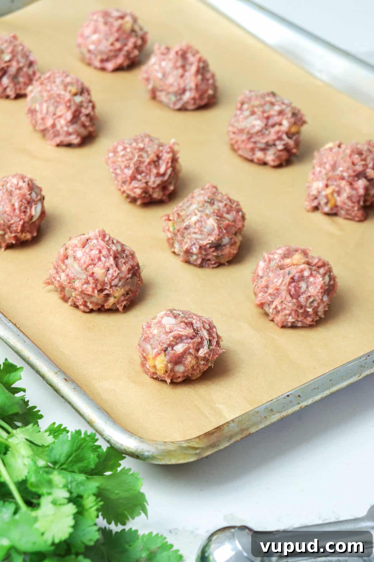 Greek Lamb Meatballs with Tzatziki Sauce Recipe 4 Raw lamb meatballs shaped into balls on a baking sheet.