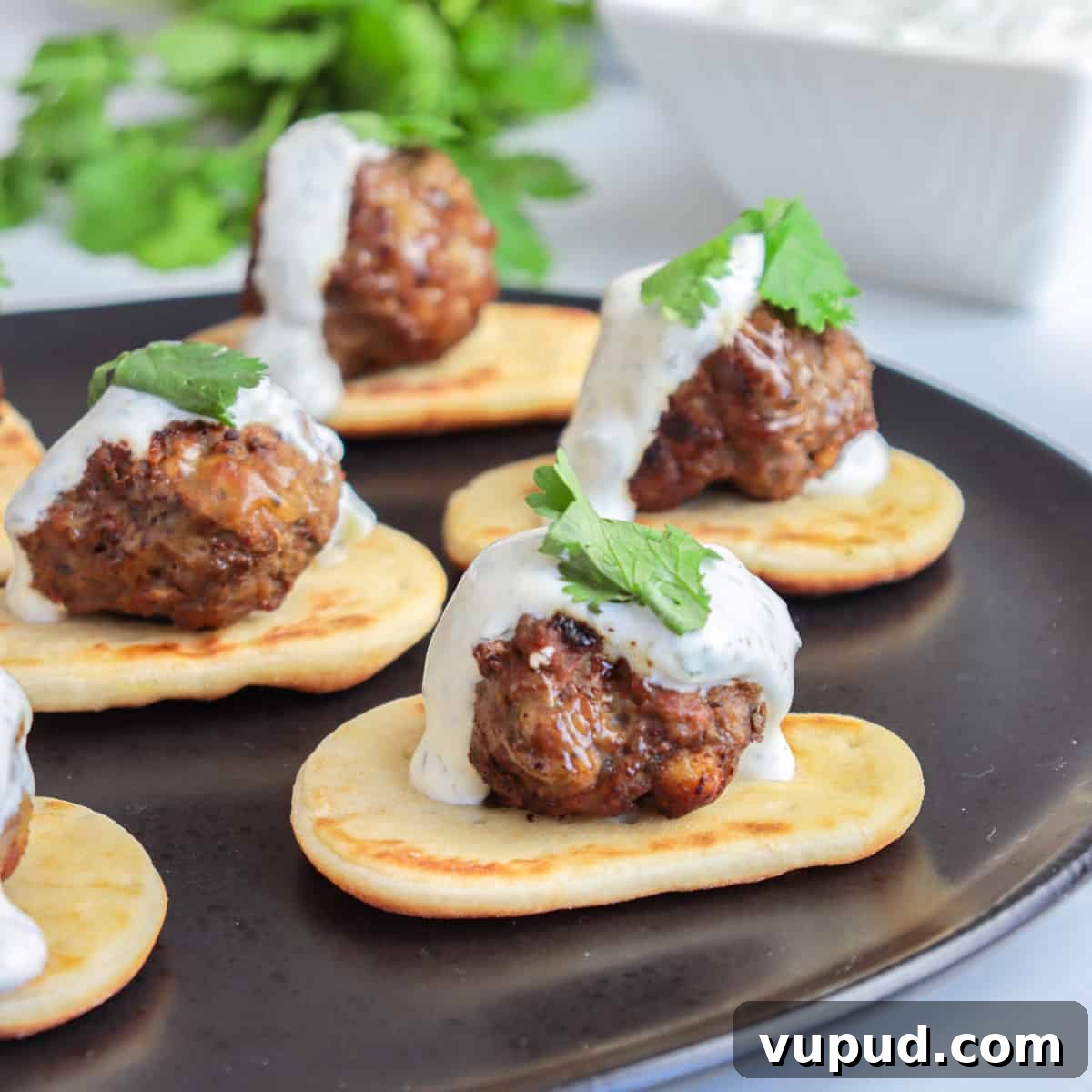 Greek Lamb Meatballs with Tzatziki Sauce Recipe 7 Lamb meatballs on top of naan with a drizzle of yogurt sauce.