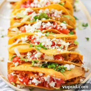 Chicken Tacos stacked on white platter with dish cloth.