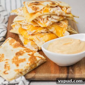Slices of chicken quesadilla stacked on a cutting board.
