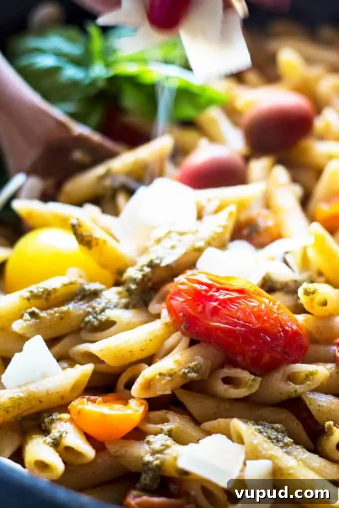 One-Pot Tomato Pesto Pasta Recipe for Quick Weeknight Meals 4 shaved parmesan being sprinkled over pasta with tomatoes and pesto