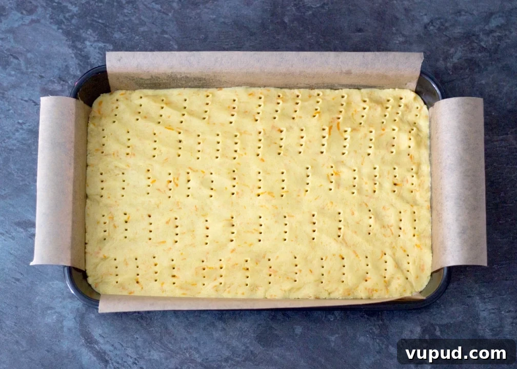Chocolate Orange Caramel Shortbread Recipe — Zesty Caramel Slice 9 Biscuit base dough pressed into a baking tray and pricked with a fork