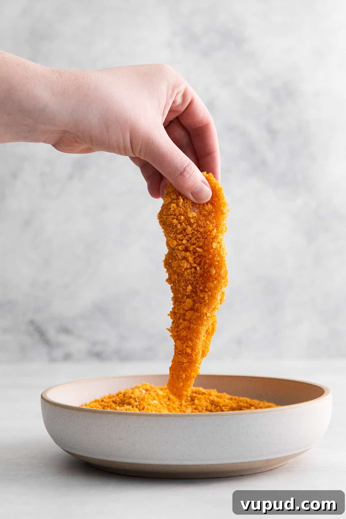 These easy Cheez-It breaded chicken fingers take one of your favorite snacks and turn it into a crispy, cheesy chicken masterpiece! Made in the air fryer in minutes. Raw chicken finger dipped in a cheez it breading.