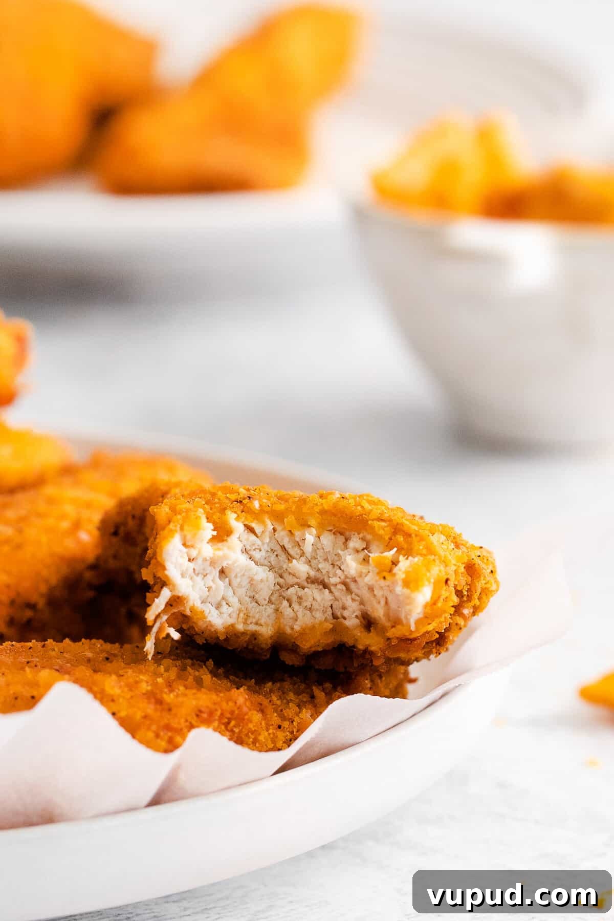 These easy Cheez-It breaded chicken fingers take one of your favorite snacks and turn it into a crispy, cheesy chicken masterpiece! Made in the air fryer in minutes. Cheez it breaded chicken finger with a bite taken out of it.