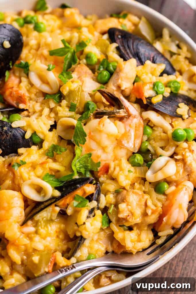 Ultimate Instant Pot Paella: Quick Spanish Rice & Seafood Recipe 2 Close-up view of Instant Pot Paella on a large neutral round plate with a fork.