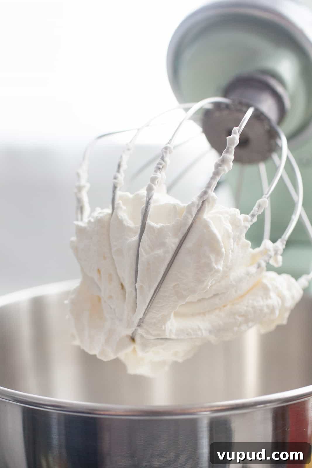 How to Make Perfect Homemade Whipped Cream at Home 5 a stand mixer filled with fresh whipped cream that's stuck in the whisk attachment