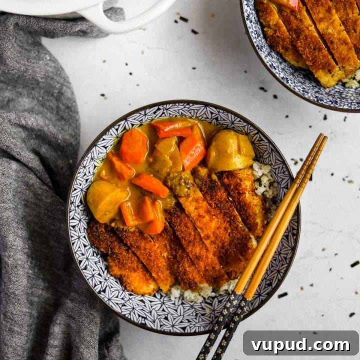 Chicken Katsu Curry in blue Japanese bowl with chopsticks and dutch oven in an overhead shot