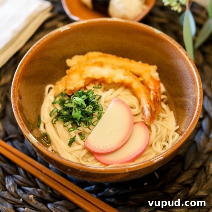 Shrimp tempura in a bowl with kamaboko and sliced green onion.