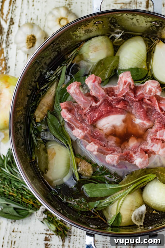 Savory Herb-Crusted Pork Crown Roast Recipe 3 A raw crown roast of pork sits in a brine with onions, garlic and fresh herbs.