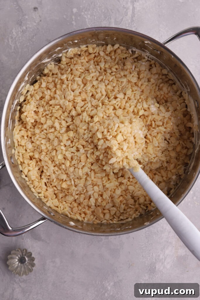 M&M Rice Krispie Treats Recipe: Colorful No-Bake Snack 7 A large pot with Rice Krispies and a white spatula in it.
