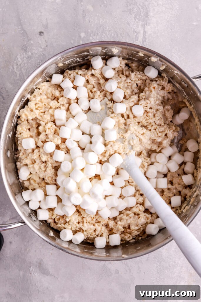 M&M Rice Krispie Treats Recipe: Colorful No-Bake Snack 8 Rice Krispie treats in a pot with mini marshmallows and a spatula.