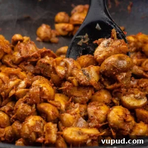 Indian Mushroom Bhaji Recipe: Flavorful Mushroom Curry Guide 12 Stirring mushroom bhaji curry with a black cooking in a pan