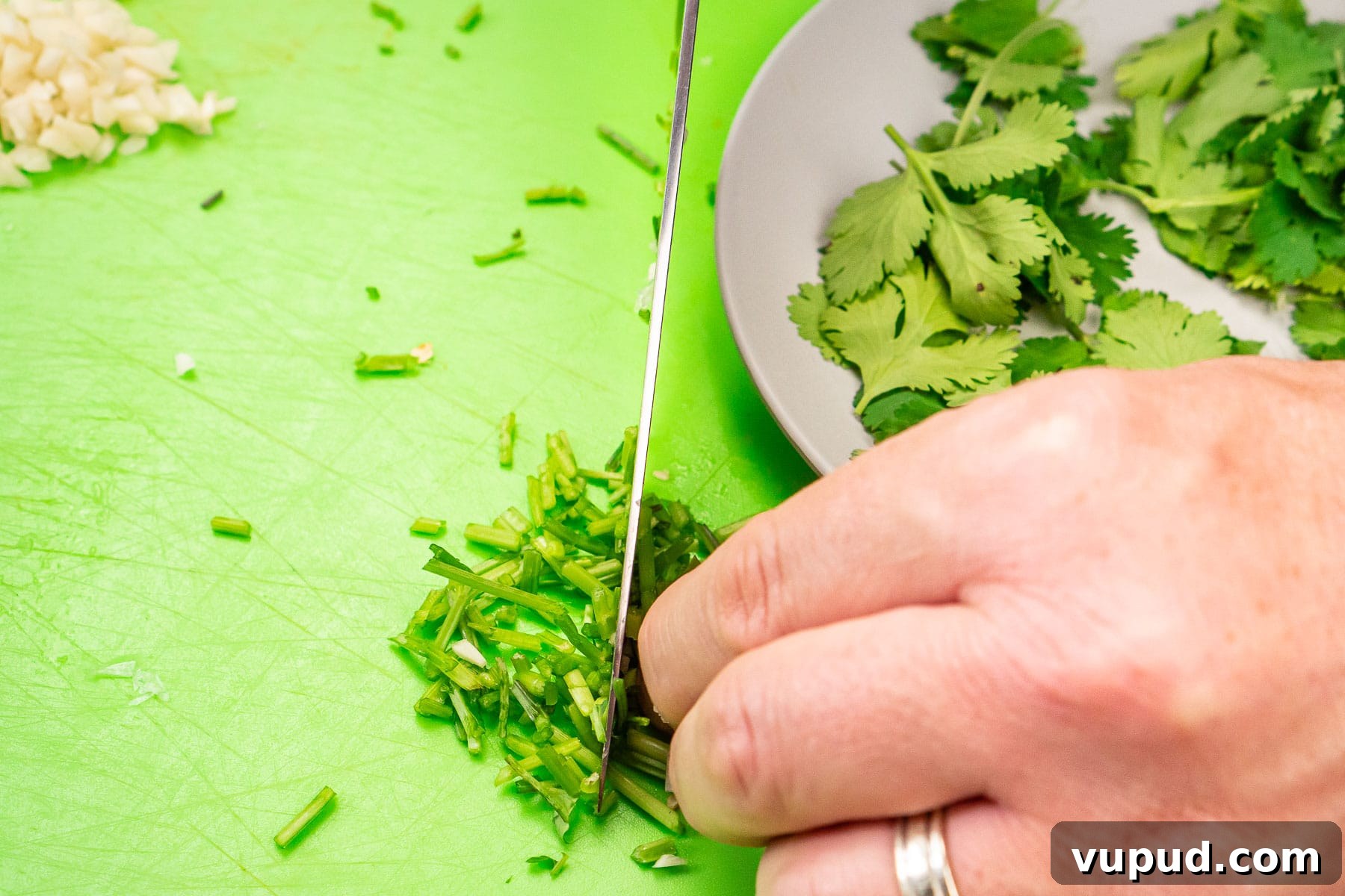 Indian Mushroom Bhaji Recipe: Flavorful Mushroom Curry Guide 16 Chopping coriander stems with a knife on a green chopping board