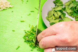 Indian Mushroom Bhaji Recipe: Flavorful Mushroom Curry Guide 5 Chopping coriander stems with a knife on a green chopping board