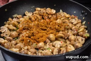 Indian Mushroom Bhaji Recipe: Flavorful Mushroom Curry Guide 9 Chopped mushrooms, chilli, onion, garlic, coriander stems and curry powder in a frying pan