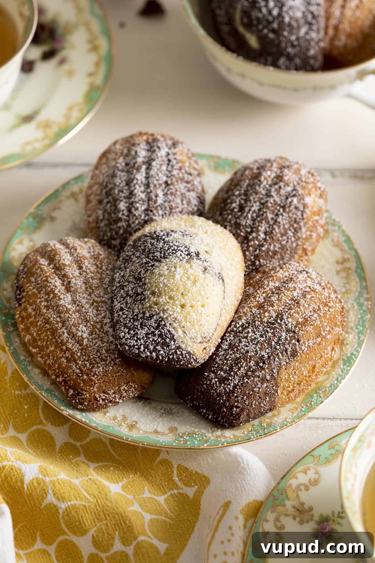 Chocolate Vanilla Marble Madeleines: Swirled French Tea Cakes 7 A plate of marble madeleines dusted with powdered sugar.