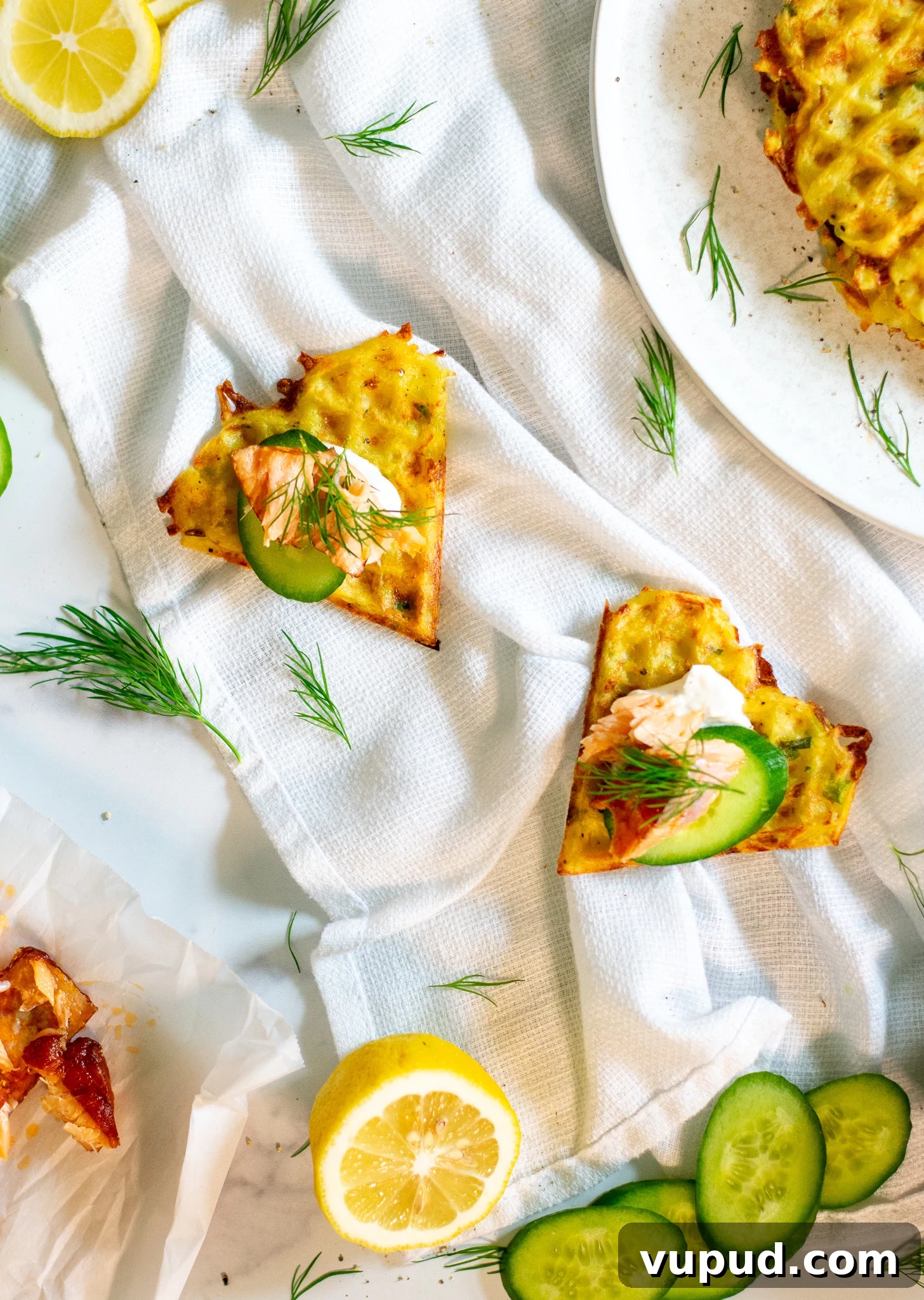 Slices of potato waffle topped with smoked salmon, cucumber, and sour cream.